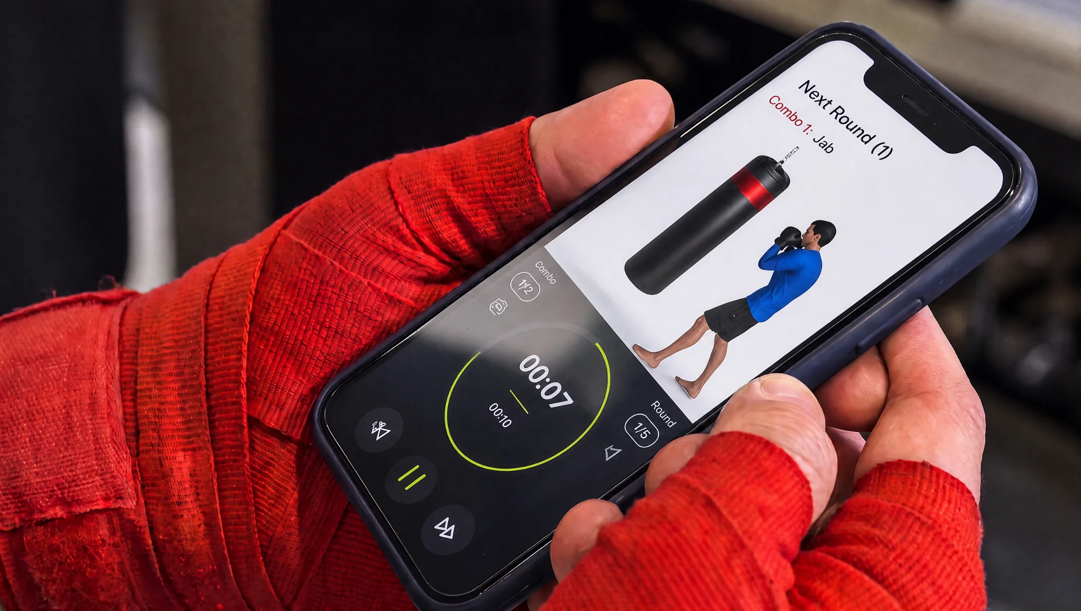 Boxer with red hand wraps holding a phone running the Heavy Bag Pro round timer